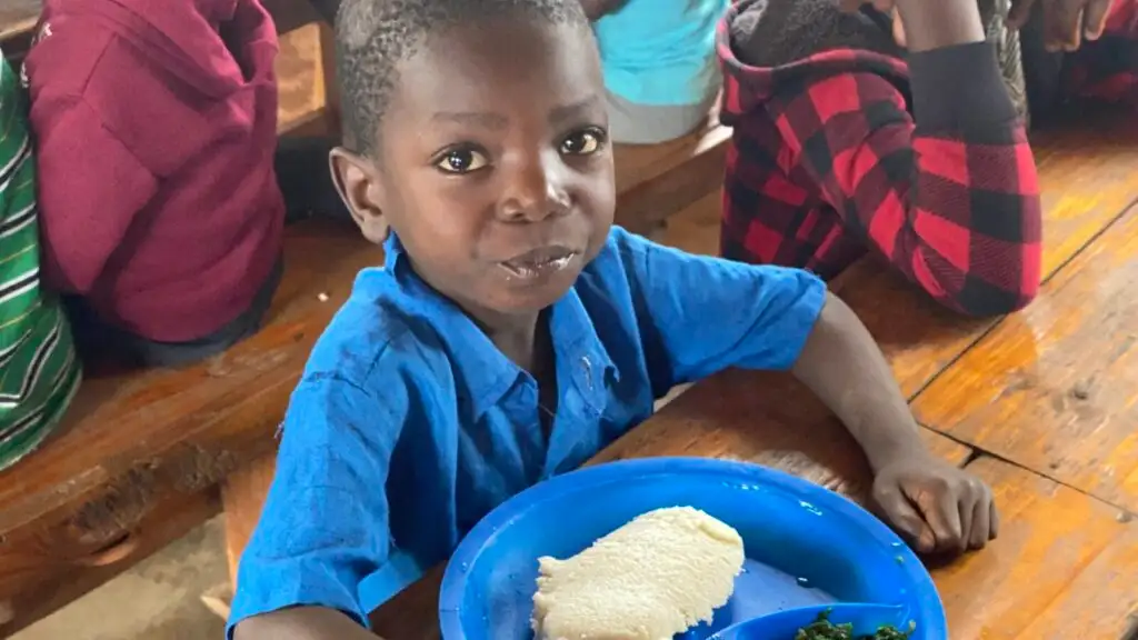 A boy at a feeding centre in Malawi with a plate of food